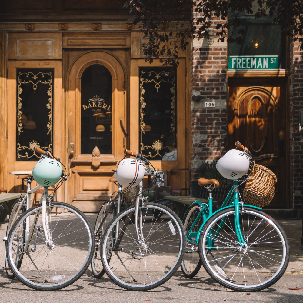 Three bicycles in a row, with helmets hanging from their handlebars